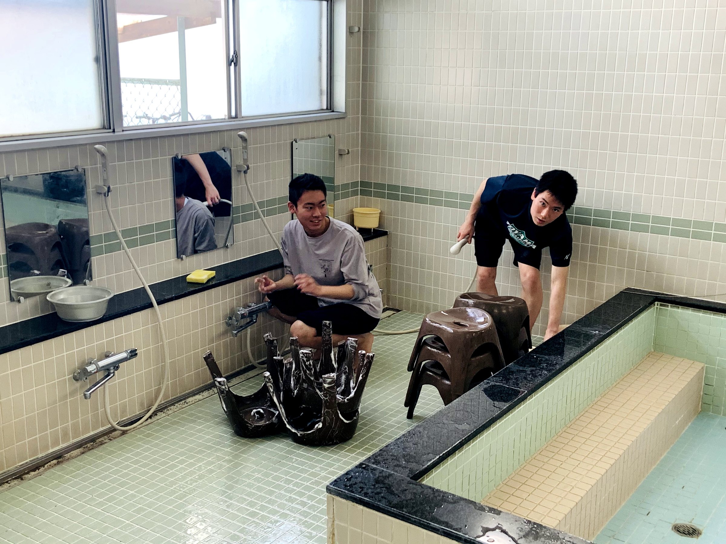 床をブラシでこする寮生