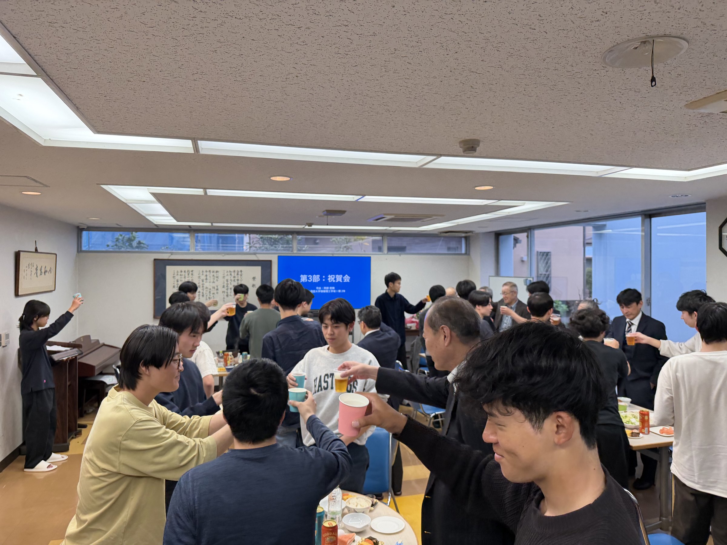 新入寮生と来賓、在寮生が食堂で乾杯する様子