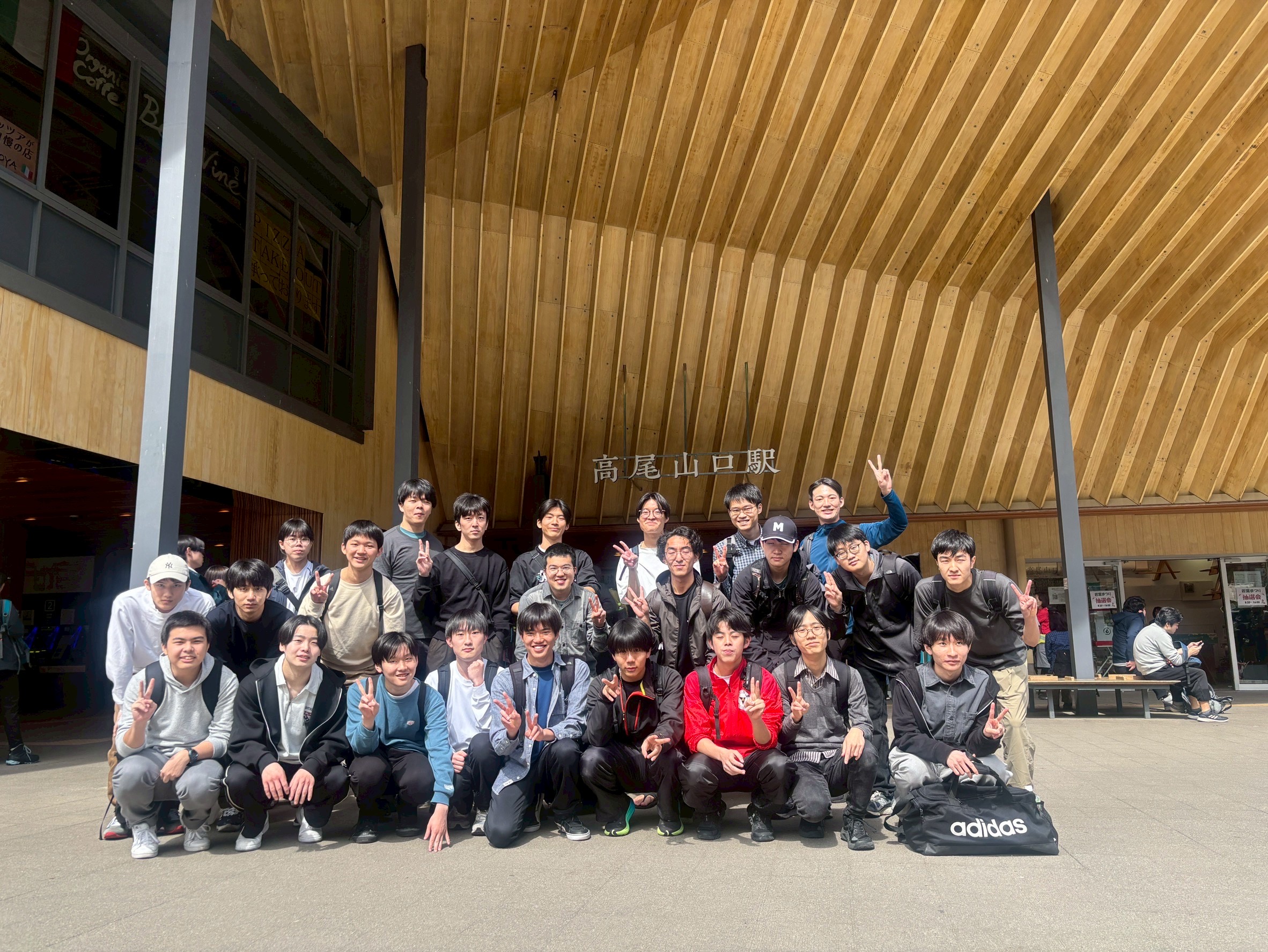 高尾山口駅に到着後、全員で集合写真を撮影する様子